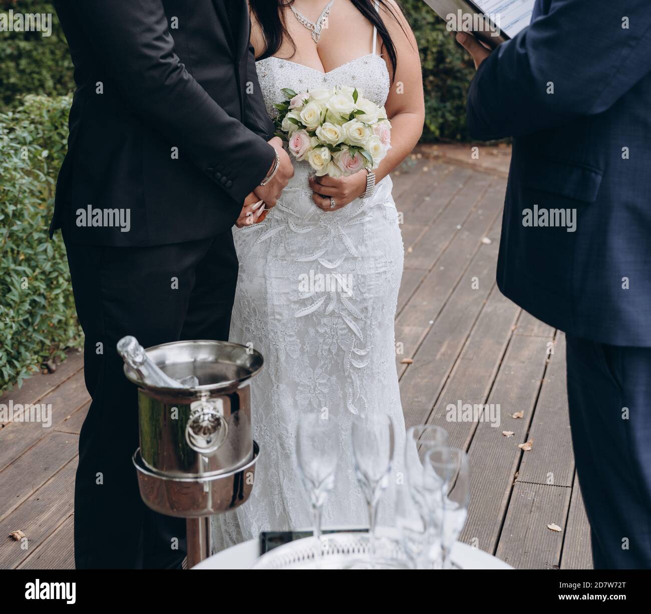 Bridal couple having their official wedding ceremony next to a registrar. Small table with cold champagne and glasses. Stock Photo