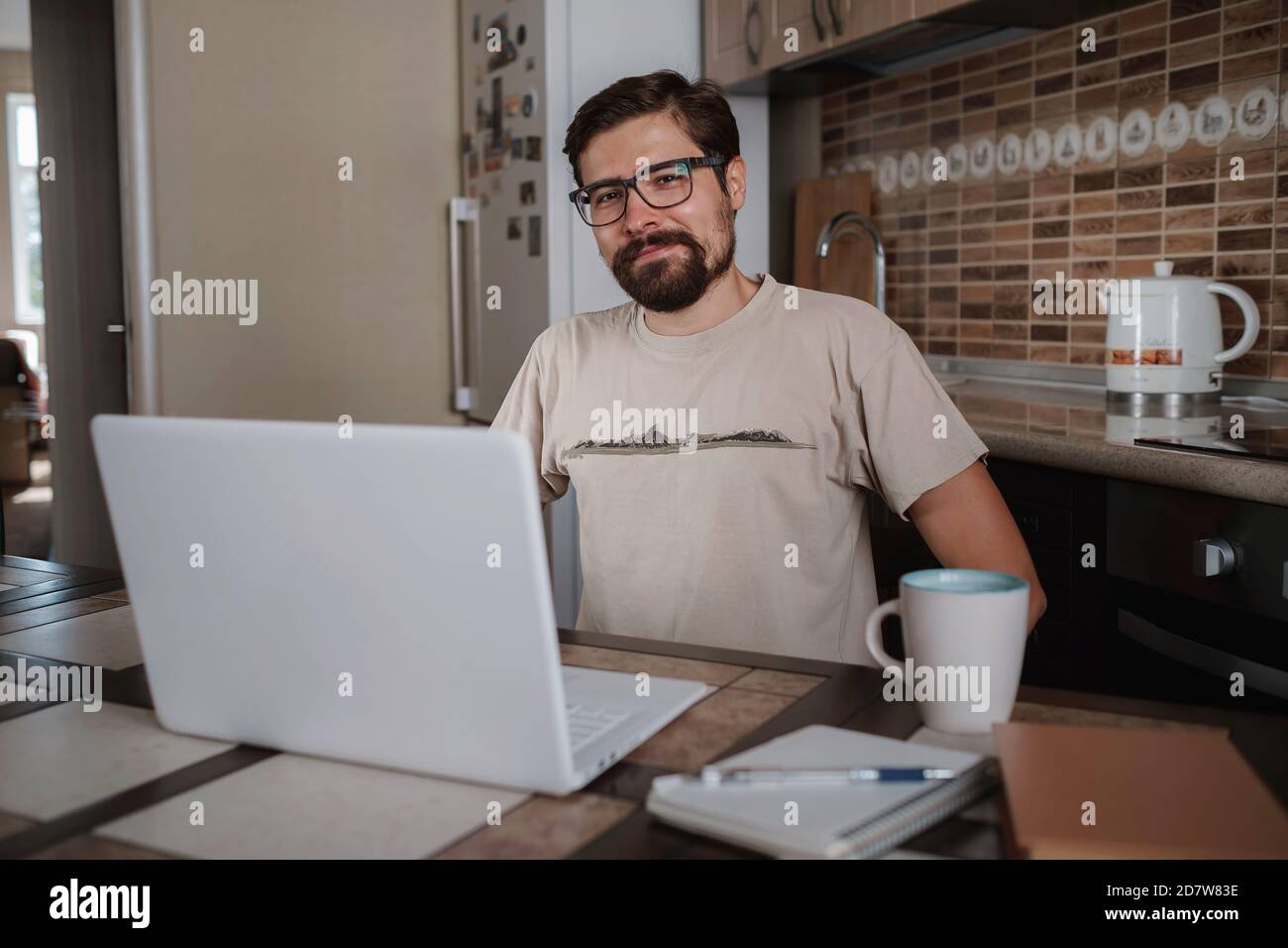 Satisfied with work done. Happy young man working on laptop while sitting at his working place in home office. Happy employee feeling no stress, relax Stock Photo