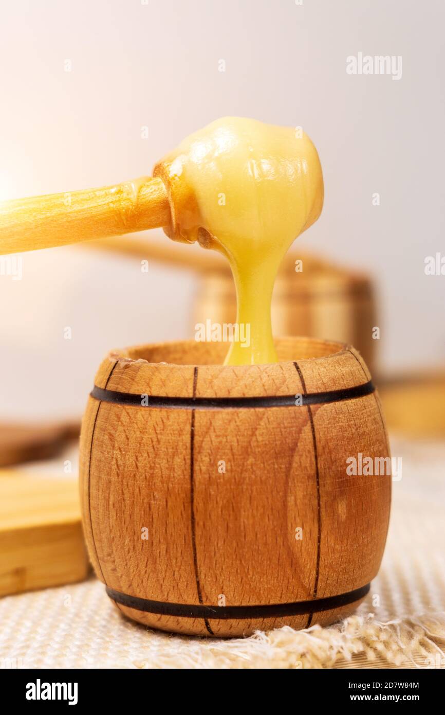 Healthy organic Thick honey dripping from the wooden honeyspoon, closeup. Sweet dessert background. vertical photo Stock Photo