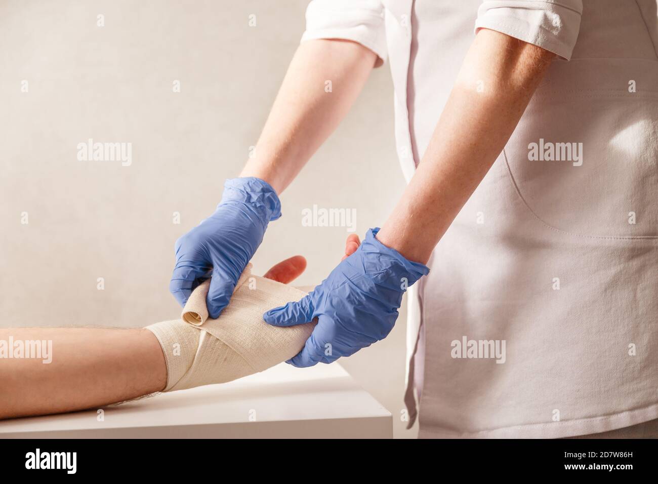 Doctor imposes an elastic bandage to the patient wrist. Rehabilitation after sprain Stock Photo