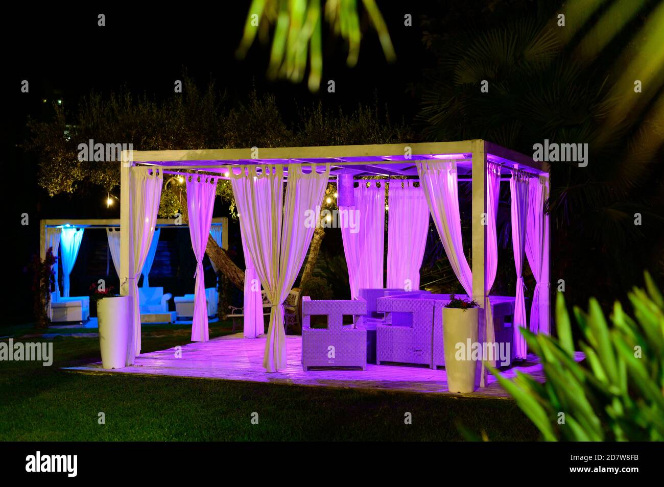 White luxury outdoor lounge terrace in green tropical garden at night