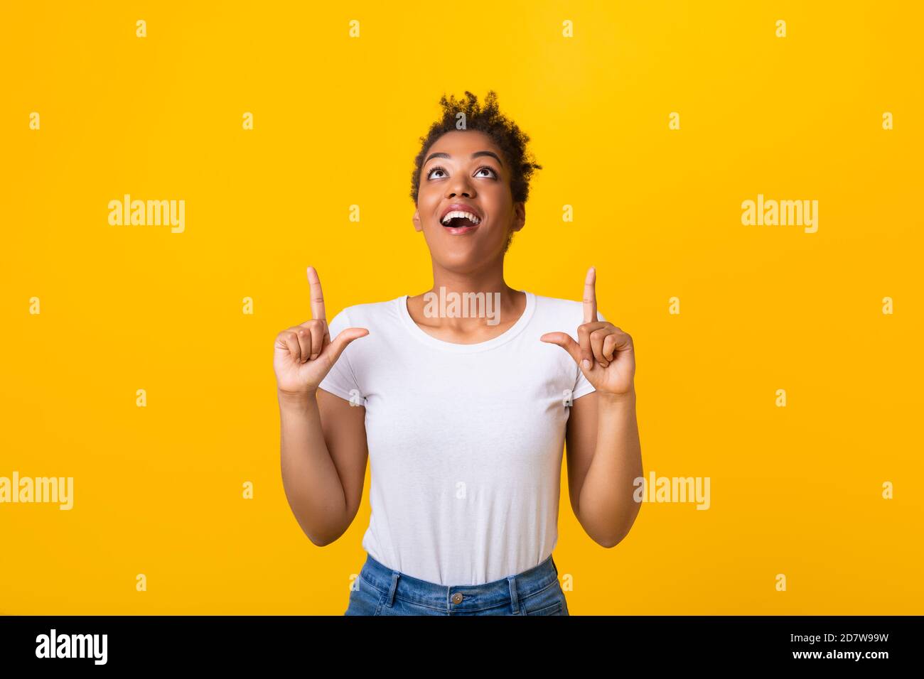 Happy afro woman pointing fingers up at copy space Stock Photo - Alamy