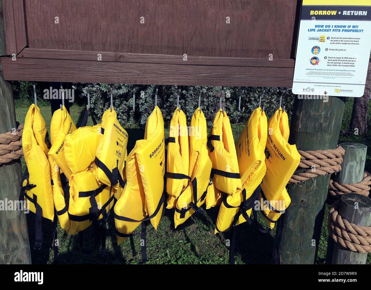 A row of bright yellow life jackets awaits boaters who have forgotten to bring a personal flotation device that helps ensure their safety at sea in the Gulf of Mexico along the west coast of Florida, USA. The buoyant vests are offered free of charge as part of a Borrow and Return program by the Sea Tow Foundation and the West Coast Inland Navigation District (WCIND). Loaner life preservers are available to prevent drownings in many places in the United States and other countries where recreation on the water is popular. Stock Photo