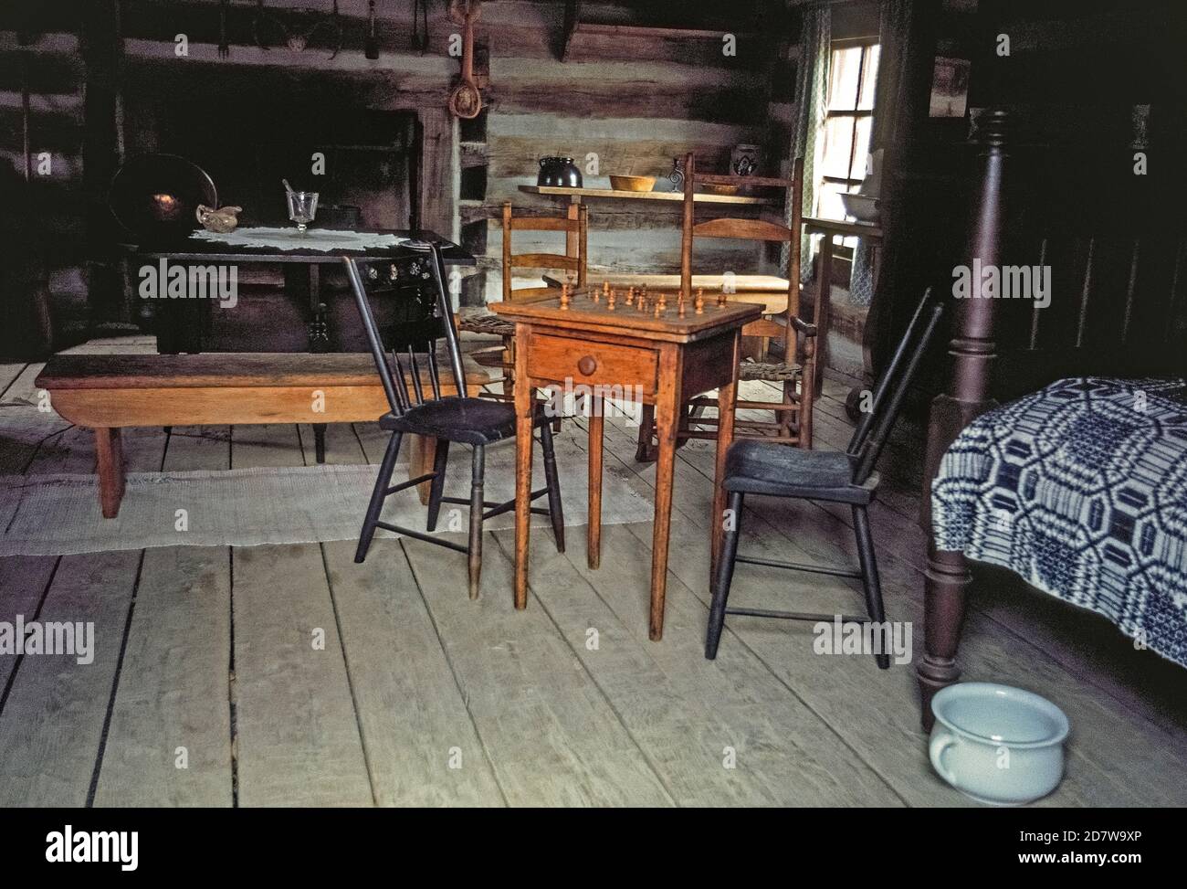 Simple furnishings are seen in the interior of this log cabin in New Salem, now an historical village that was once home to Abraham Lincoln, 16th President of the United States. He moved to the small central Illinois settlement in 1831 at the age of 22 and stayed for six years before becoming a lawyer and politician. Notable is the chess board with wooden playing pieces, and a porcelain chamber pot next to the bed. New Salem only existed for about a dozen years before being abandoned. Reconstructed in the 1930-40s by the Civilian Conservation Corps (CCC), it features 23 log buildings. Stock Photo