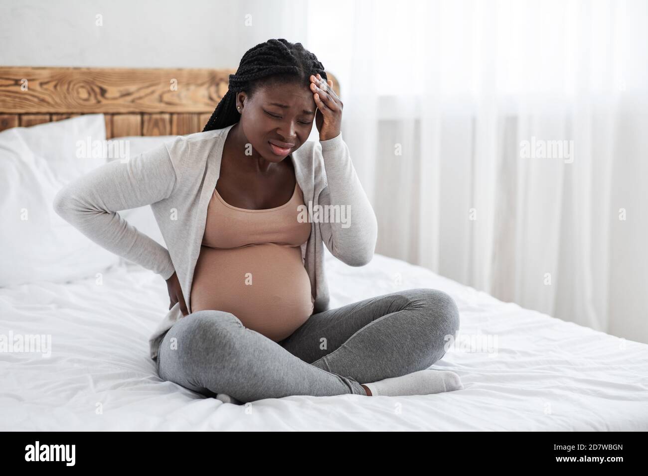 Migraine During Pregnancy. Black pregnant woman suffering from strong headache at home Stock Photo