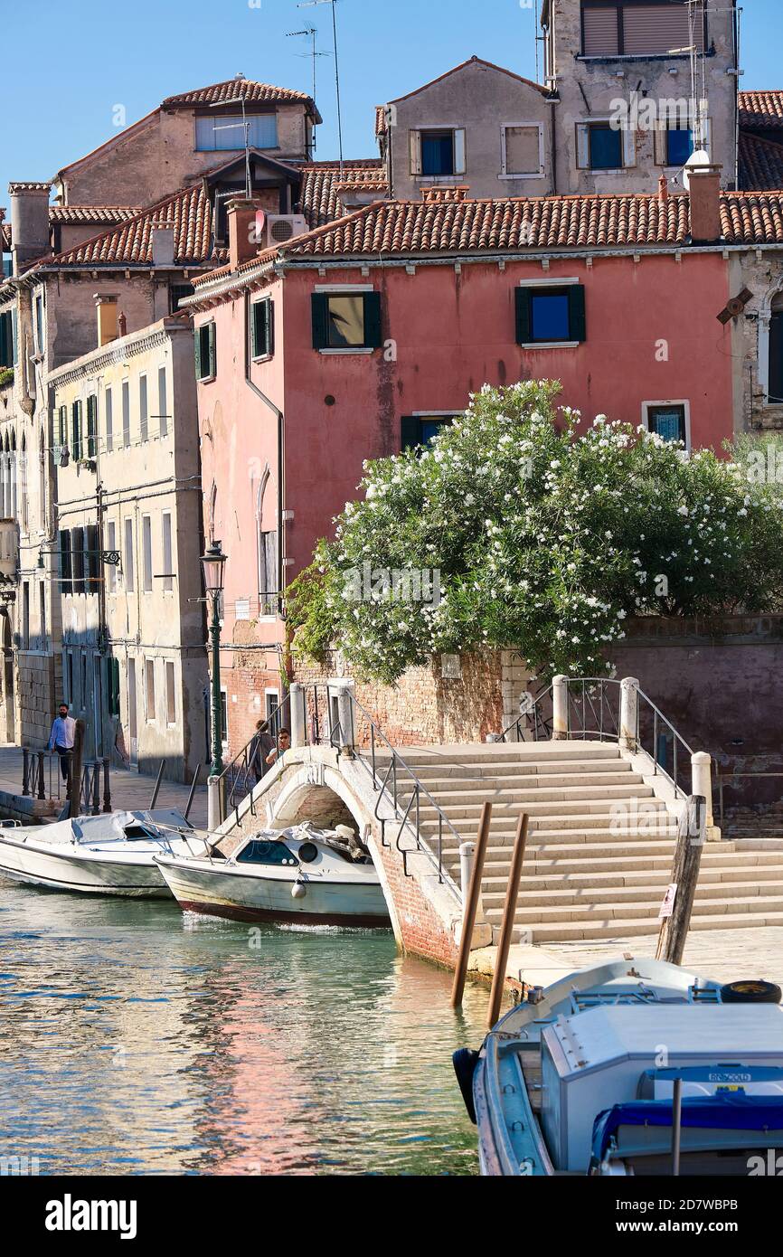 Romantic old houses and pedestrian bridge across canal. Hardly anybody outdoors. Tourists are returning to Venice, but far fewer than in recent years. Stock Photo