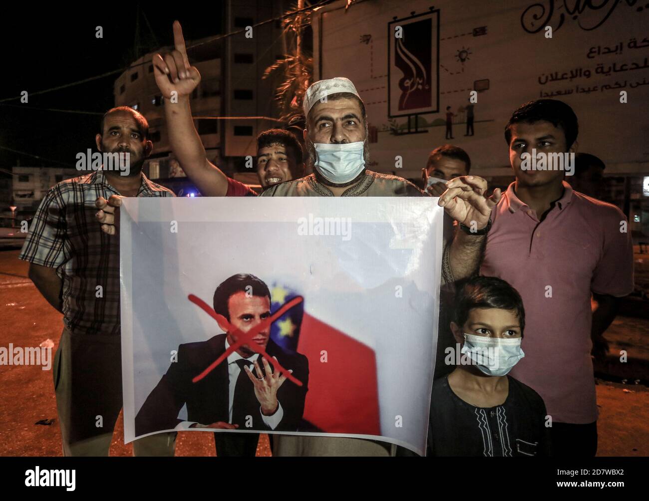 Protester holding a placard with a crossed out image of the French president during the demonstration.Palestinians in the city of Rafah protest against the publishing of cartoons as Prophet Muhammad in a French newspaper and the statement of French President Emmanuel Macron. Stock Photo