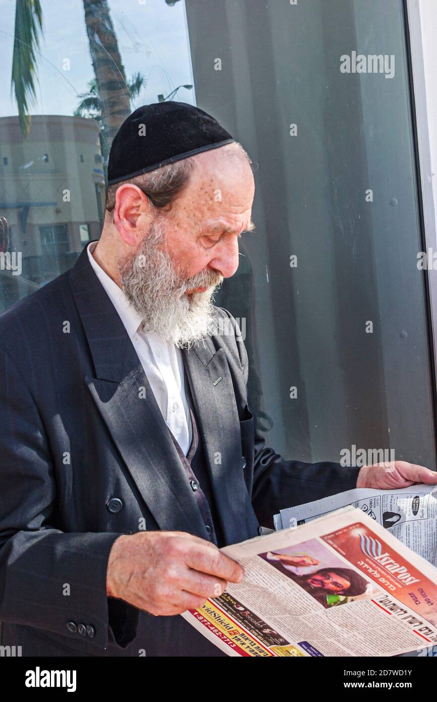Miami Beach Florida,Orthodox Jew Jewish faith,reading tabloid man senior beard wears wearing yarmulka kippah, Stock Photo