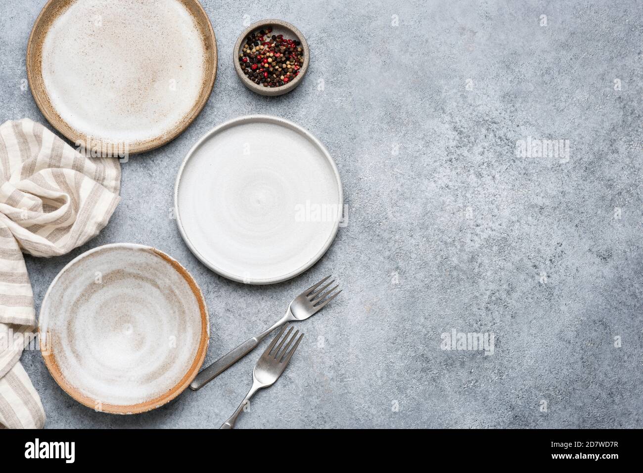 Table setting with trendy grey ceramic plates on grey concrete background. Top view Stock Photo