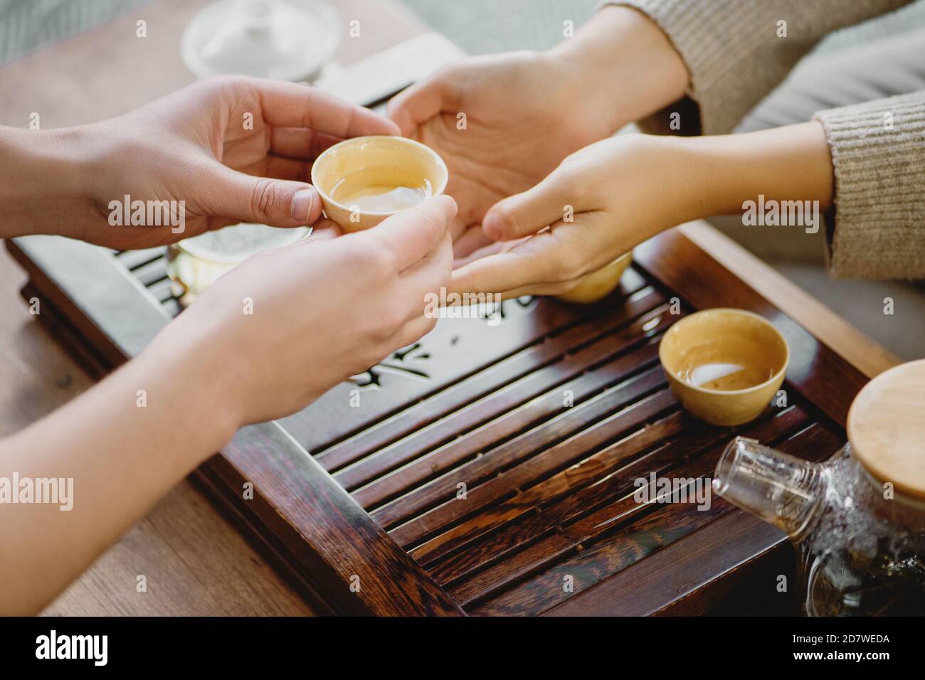 Closeup of male hands giving small porcelain cup with tea to female during a tea ceremony. Stock Photo