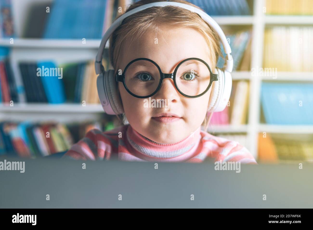 Smart little girl wearing big glasses while using her laptop computer. High quality photo Stock Photo