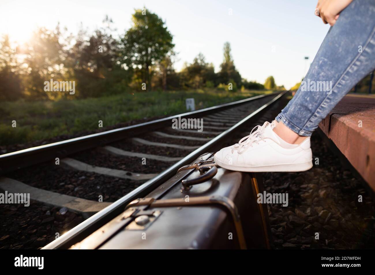 Travel suitcase. Sports shoes. Railroad tracks. In the glow of the