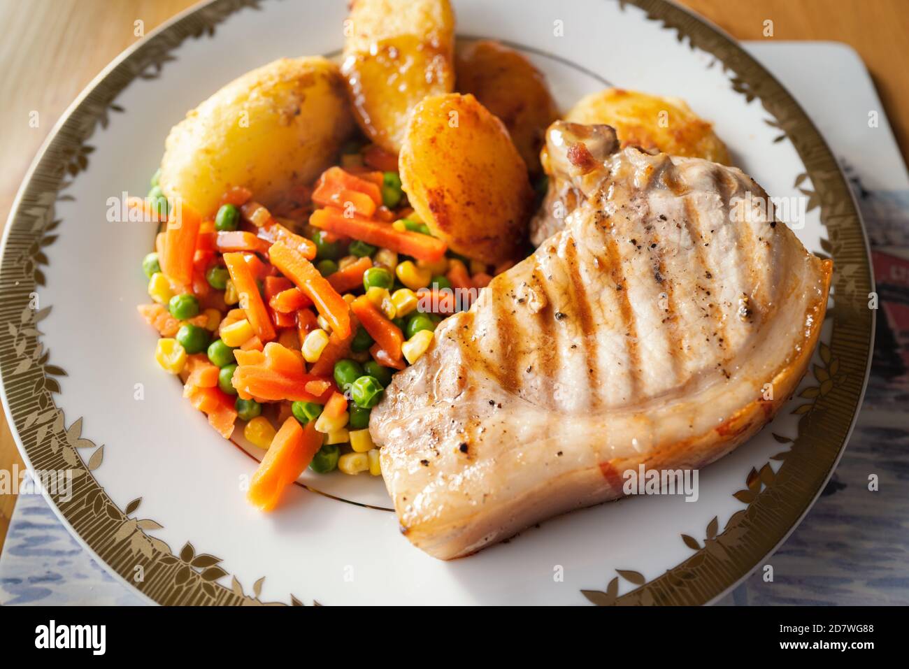 Pork chop with mixed vegetables, roast potatoes and gravy. Home cooked