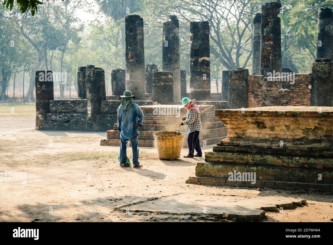 Thai workers cleaning Sukhothai site from dead leaves on the ground near Wat Si Chum, Sukhothai, Thailand Stock Photo