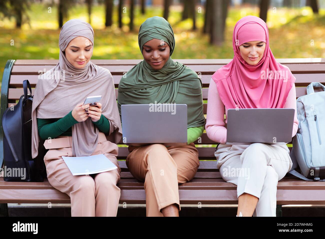 Arab Ladies Using Smartphone And Computers Learning Online In Park Stock Photo