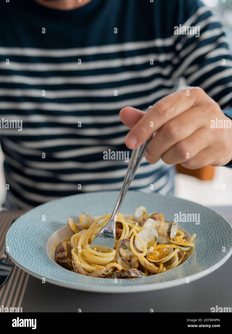 detail male hand eating pasta spaghetti with clams and mullet, Mediterranean food Stock Photo