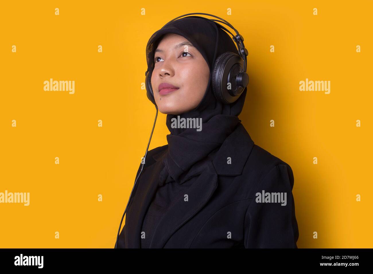 Asian muslim woman with hijab listening to music on headphones isolated ...
