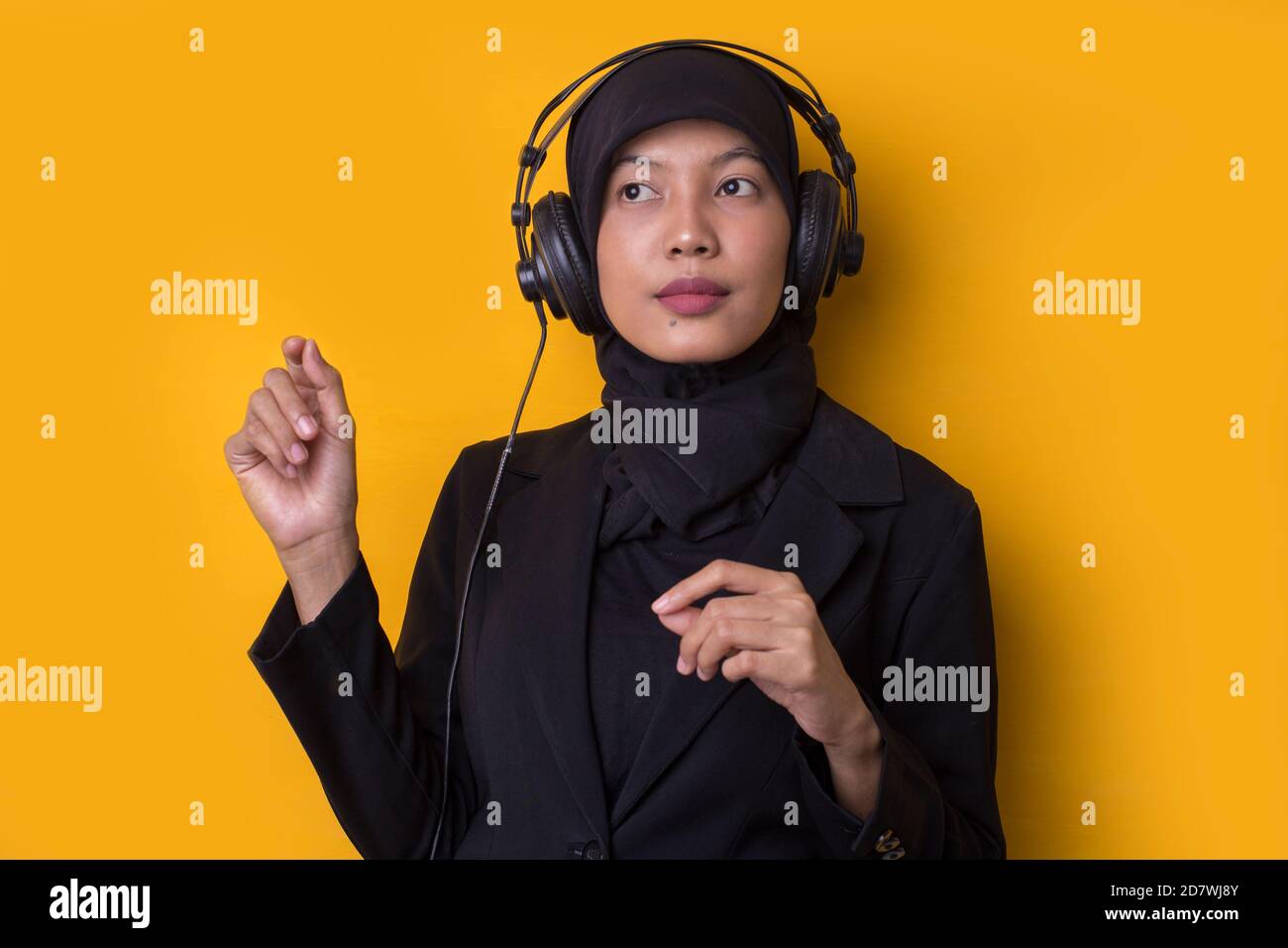Asian muslim woman with hijab listening to music on headphones isolated ...