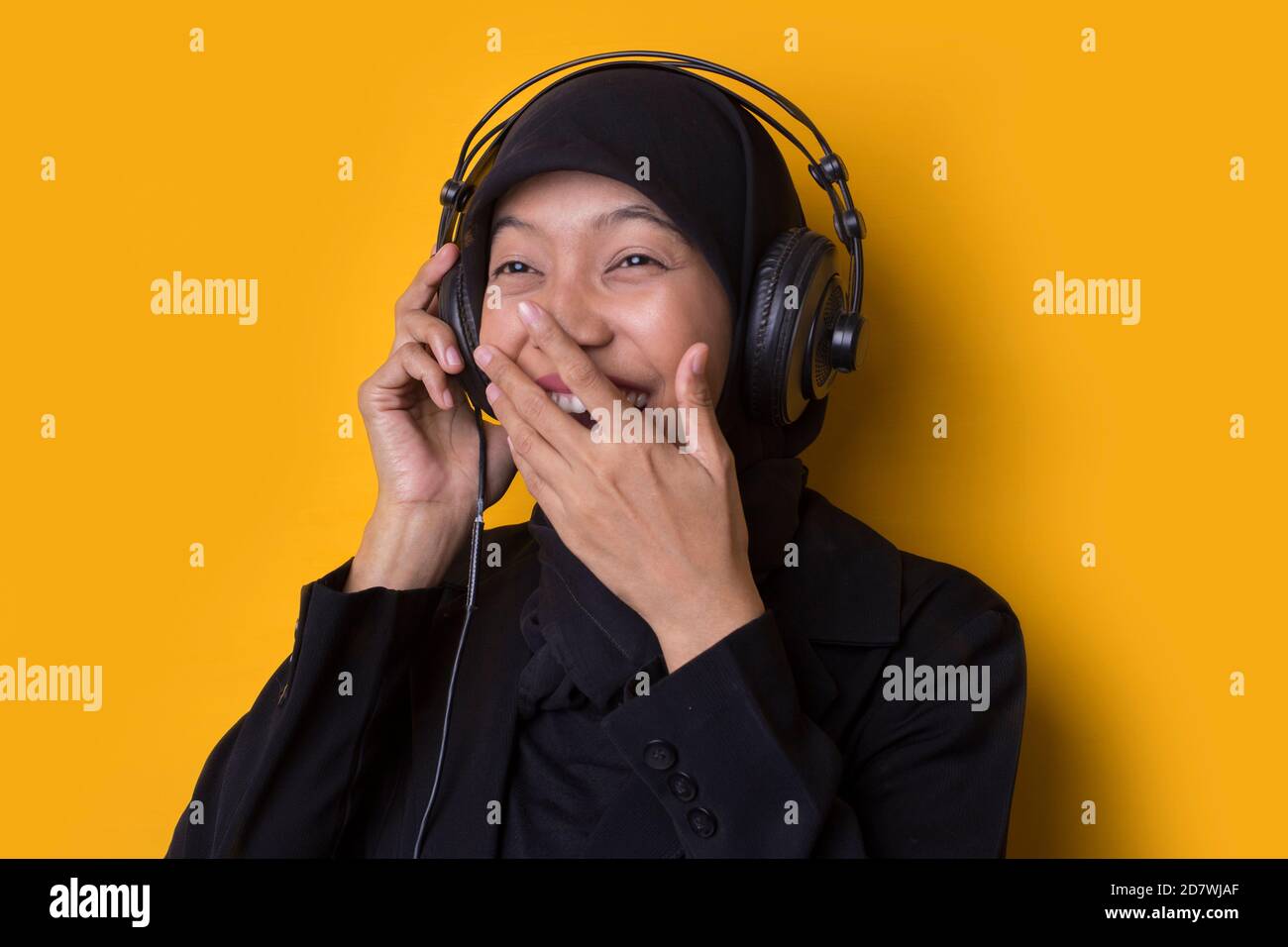 Asian muslim woman with hijab listening to music on headphones isolated ...