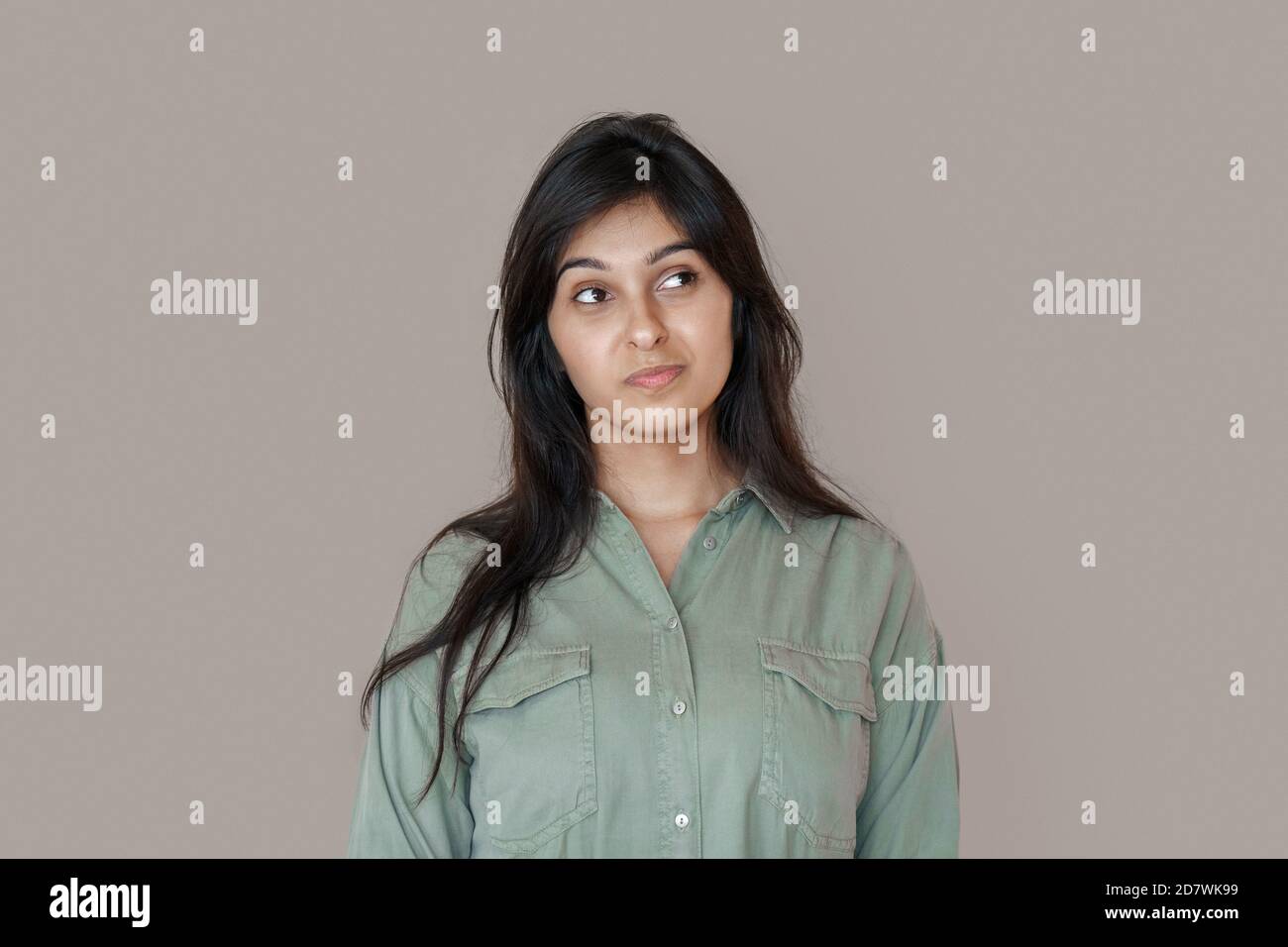 Doubtful young indian woman looking at copy space, dreaming or choosing. Stock Photo