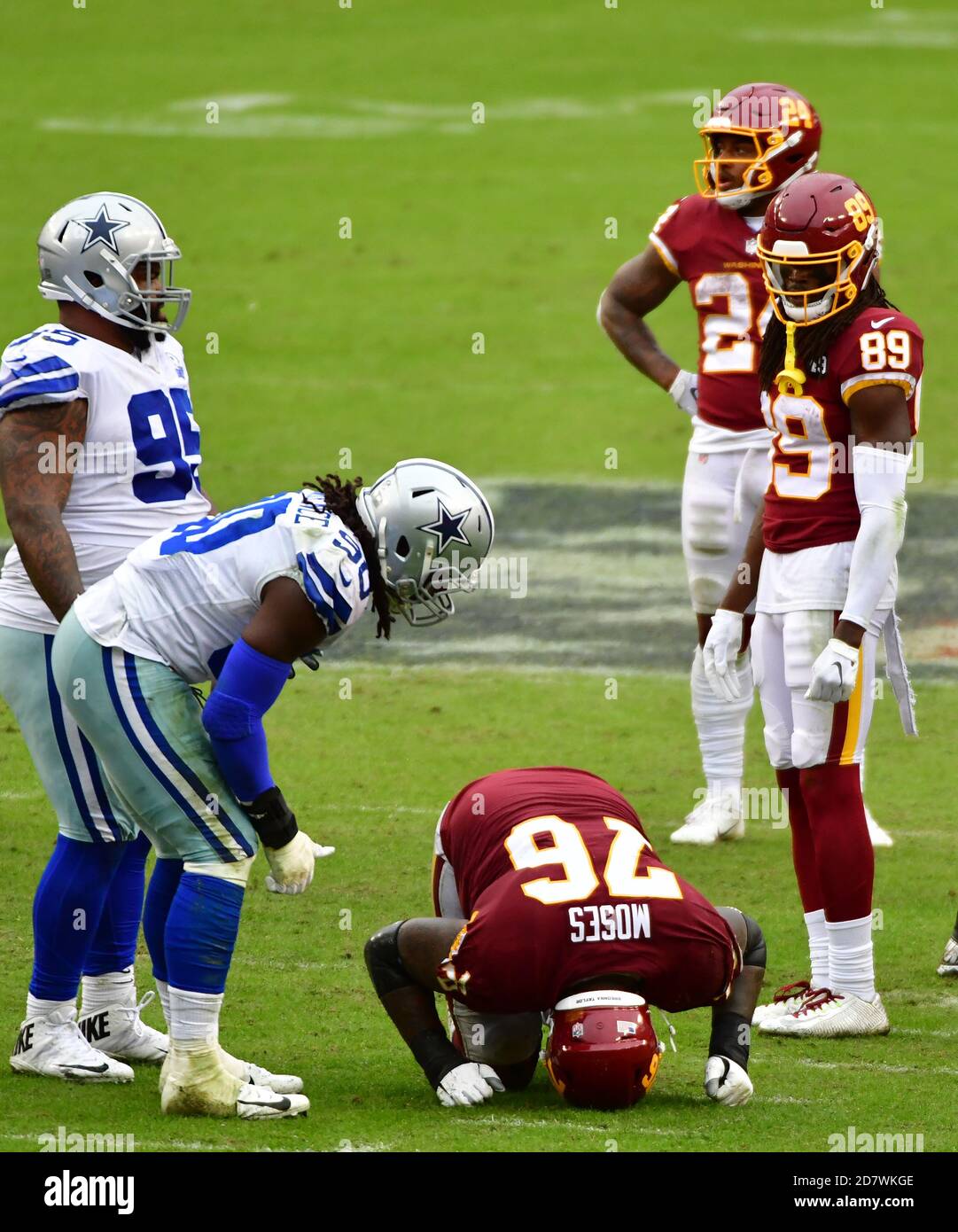 Landover, United States. 25th Oct, 2020. Dallas Cowboys defensive end  DeMarcus Lawrence (90) checks on injured Washington Football Team offensive  tackle Morgan Moses (76) during the second half of an NFL football