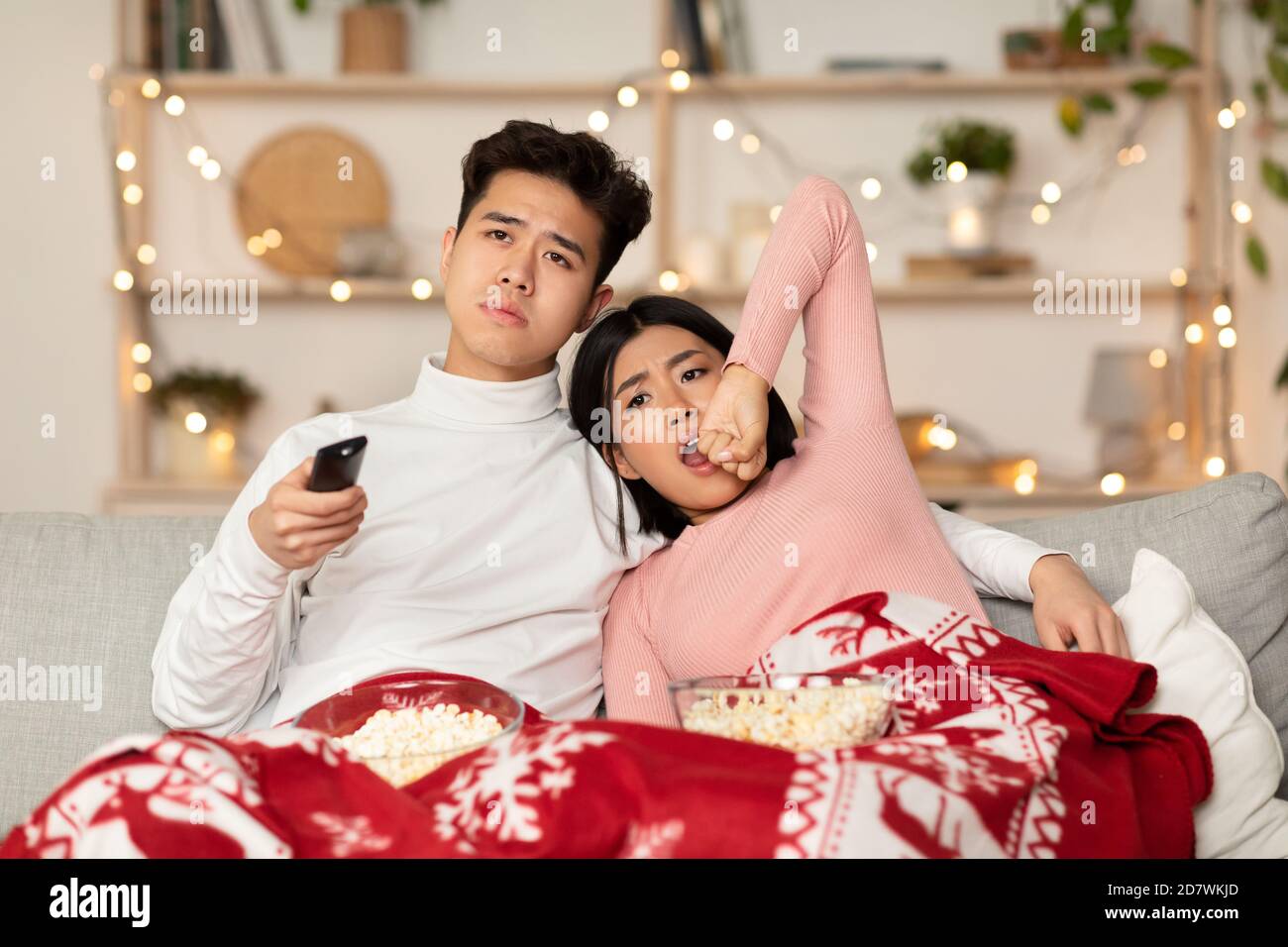 Bored Chinese Couple Watching TV Yawning Celebrating Christmas At Home Stock Photo