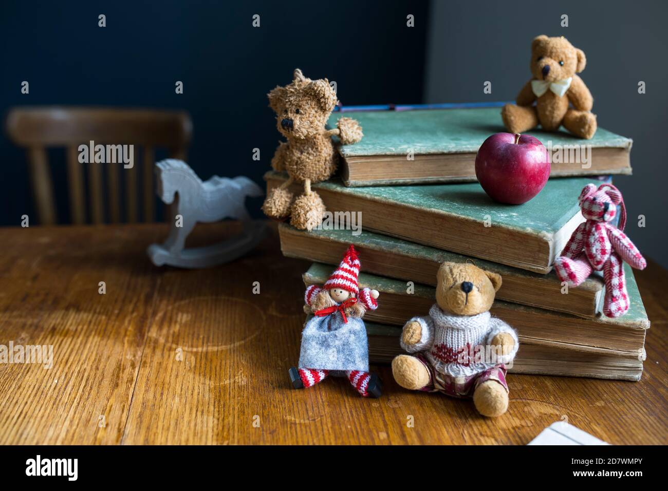 A Christmas doll and bears sit on a stack of old books. Copy space. Selective focus Stock Photo