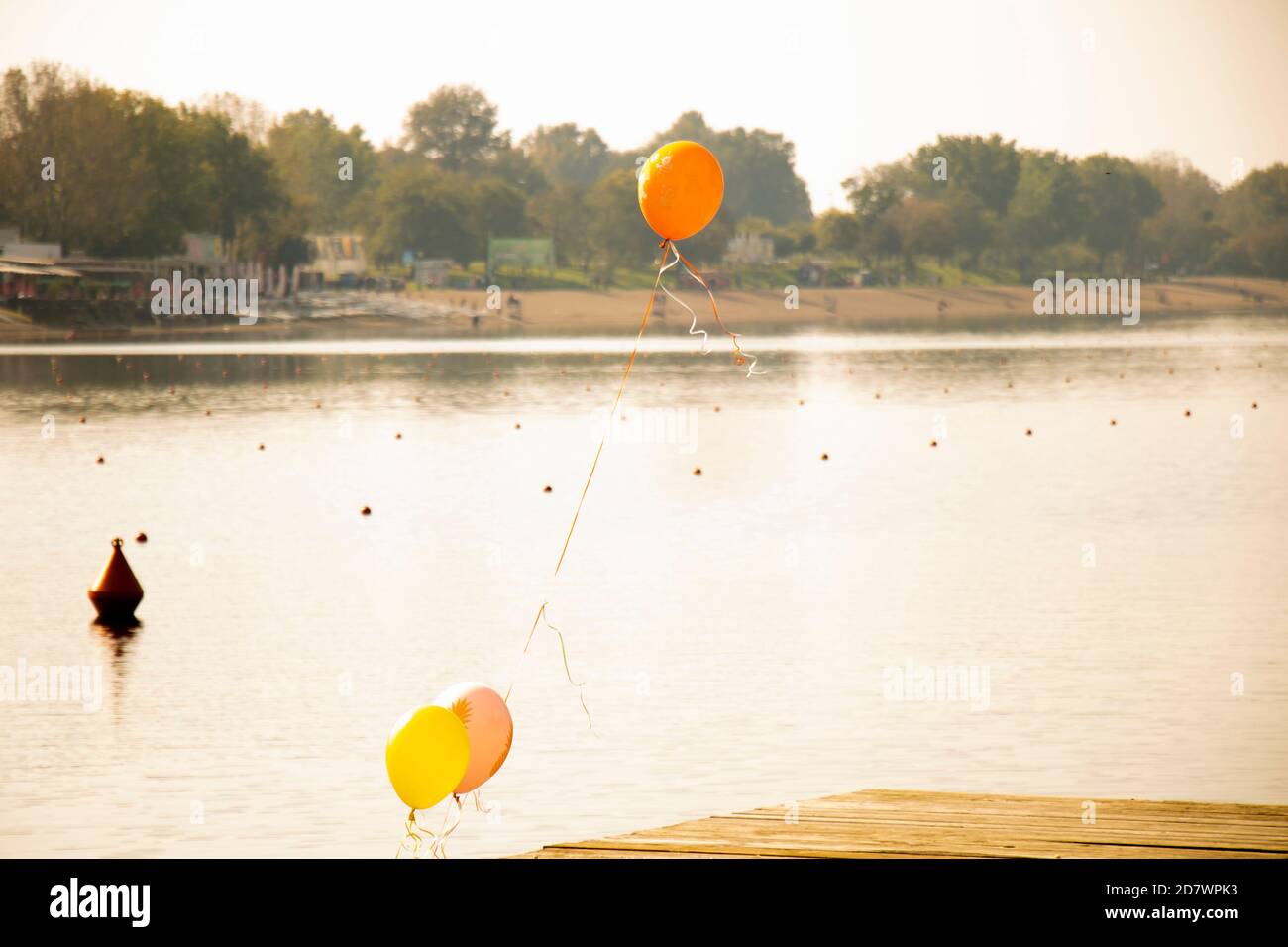 Celebration balloons tied up on a pier on a lake in sunset Stock Photo