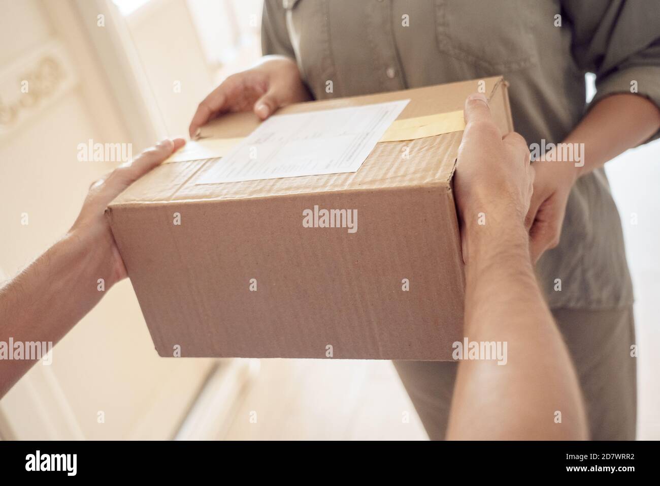 Female customer receiving courier service delivery parcel box at home, close up. Stock Photo
