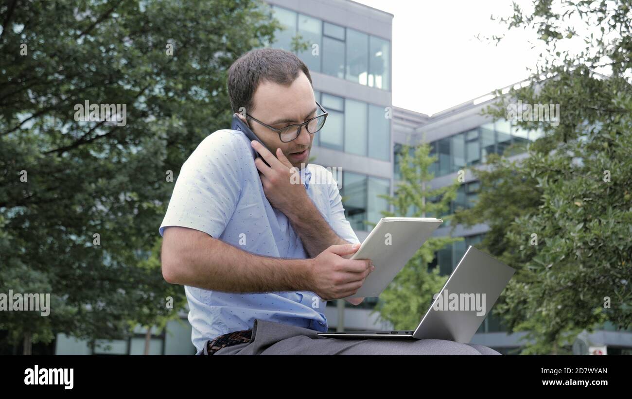 Business man using tablet and laptop while talking on smartphone Stock Photo