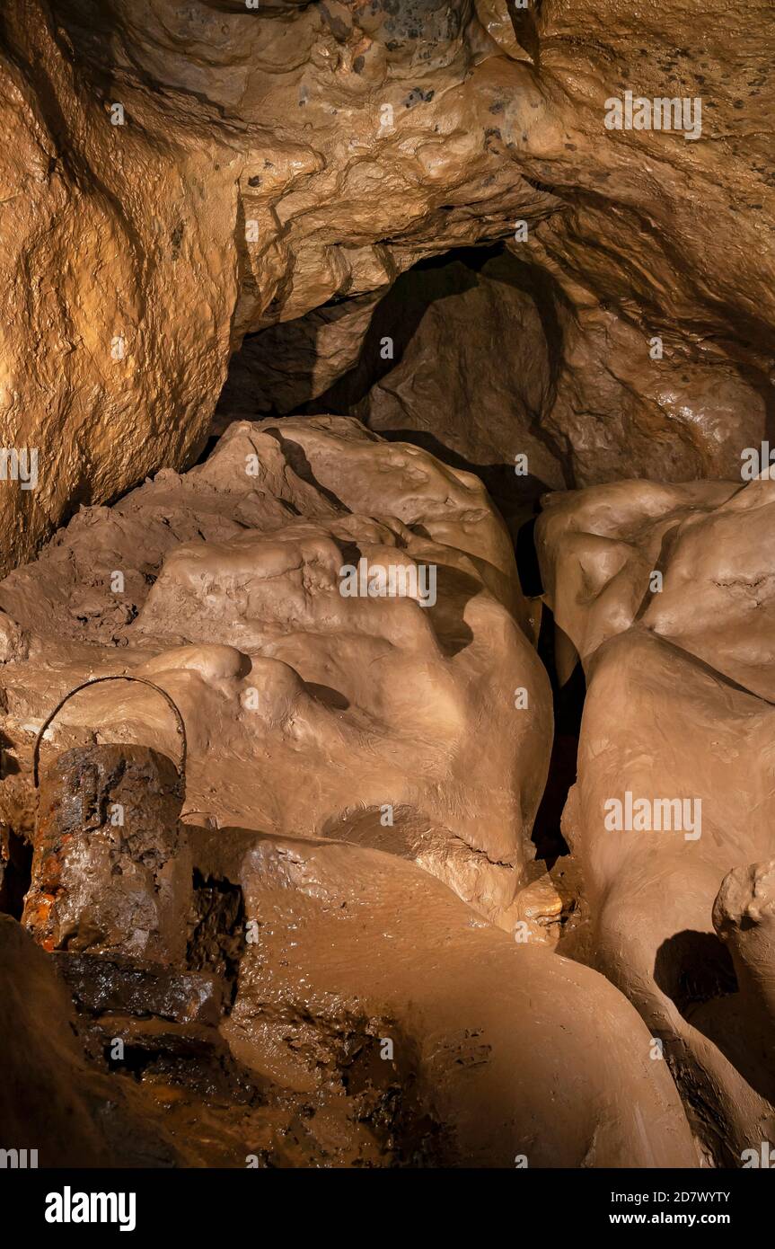 The very muddy approach to Moss Chamber from Pickering's Passage in Peak Cavern, with a very rusty old bucket at left, presumably from a digging trip. Stock Photo