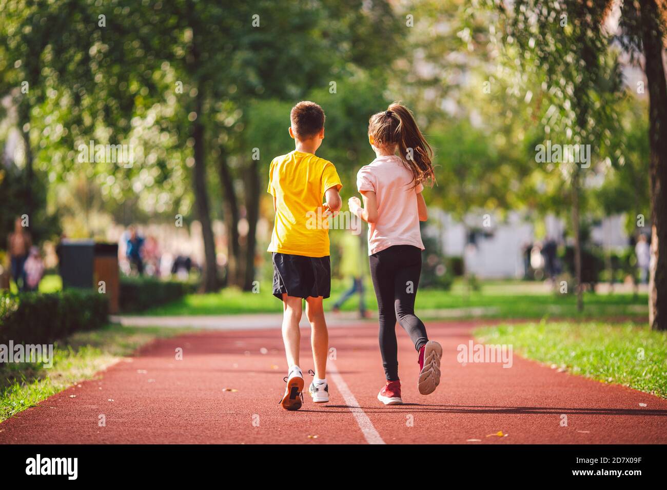 Couple of kids boy and girl doing cardio workout, jogging in park on  jogging track red. Cute twins runing together. Run children, young  athletes. Teen Stock Photo - Alamy