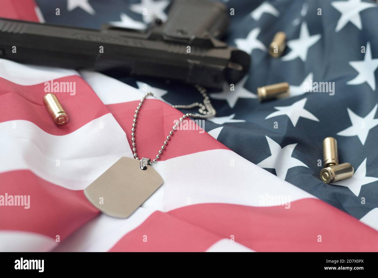Army Dog tag token with 9mm bullets and pistol lie on folded United ...