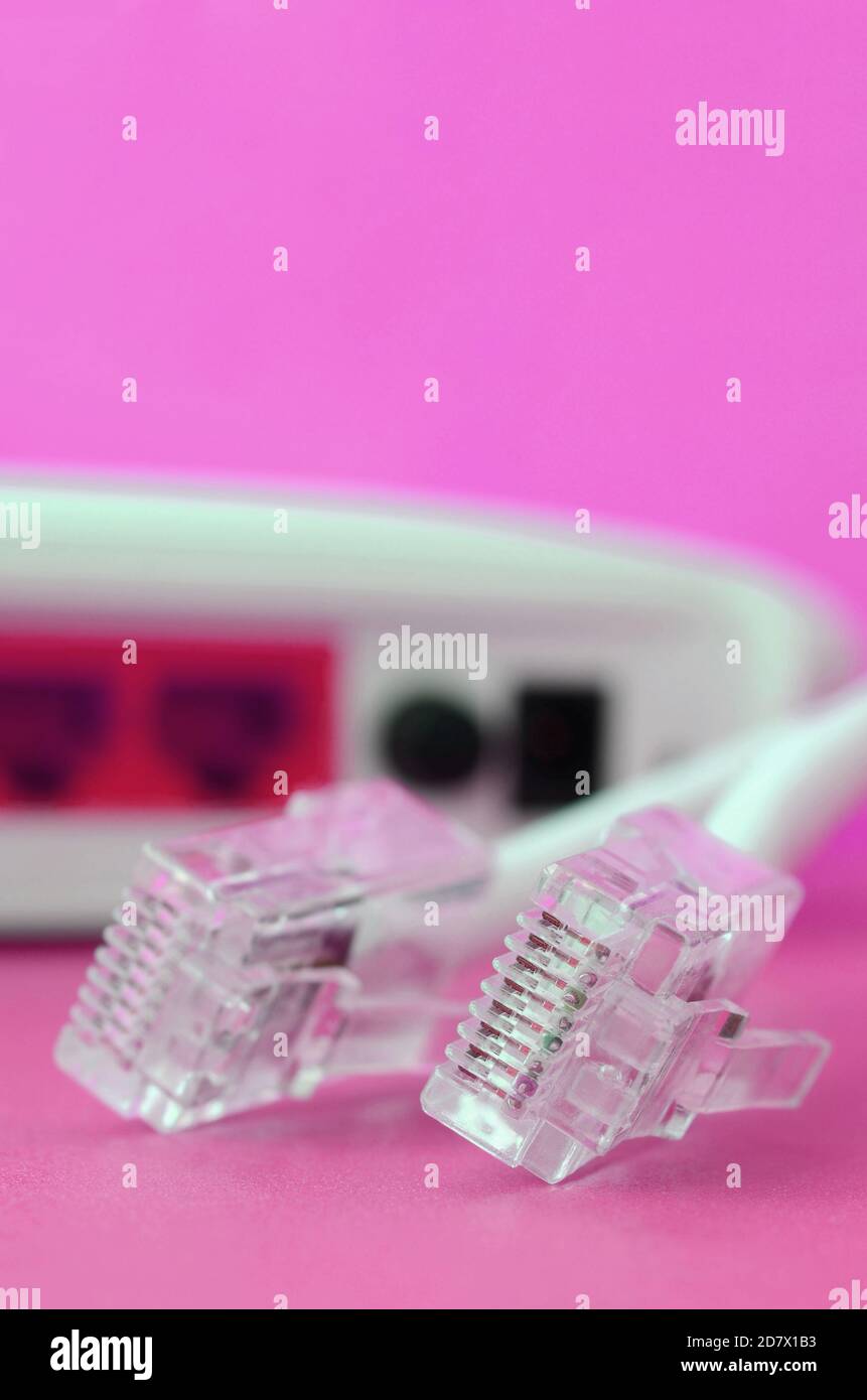 Internet router and Internet cable plugs lie on a bright pink ...