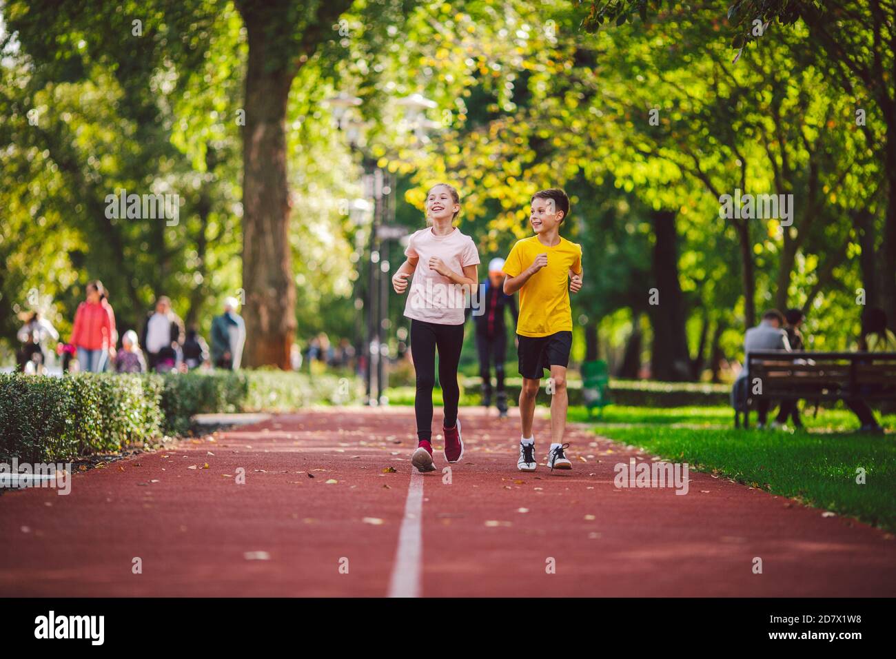Couple of kids boy and girl doing cardio workout, jogging in park on