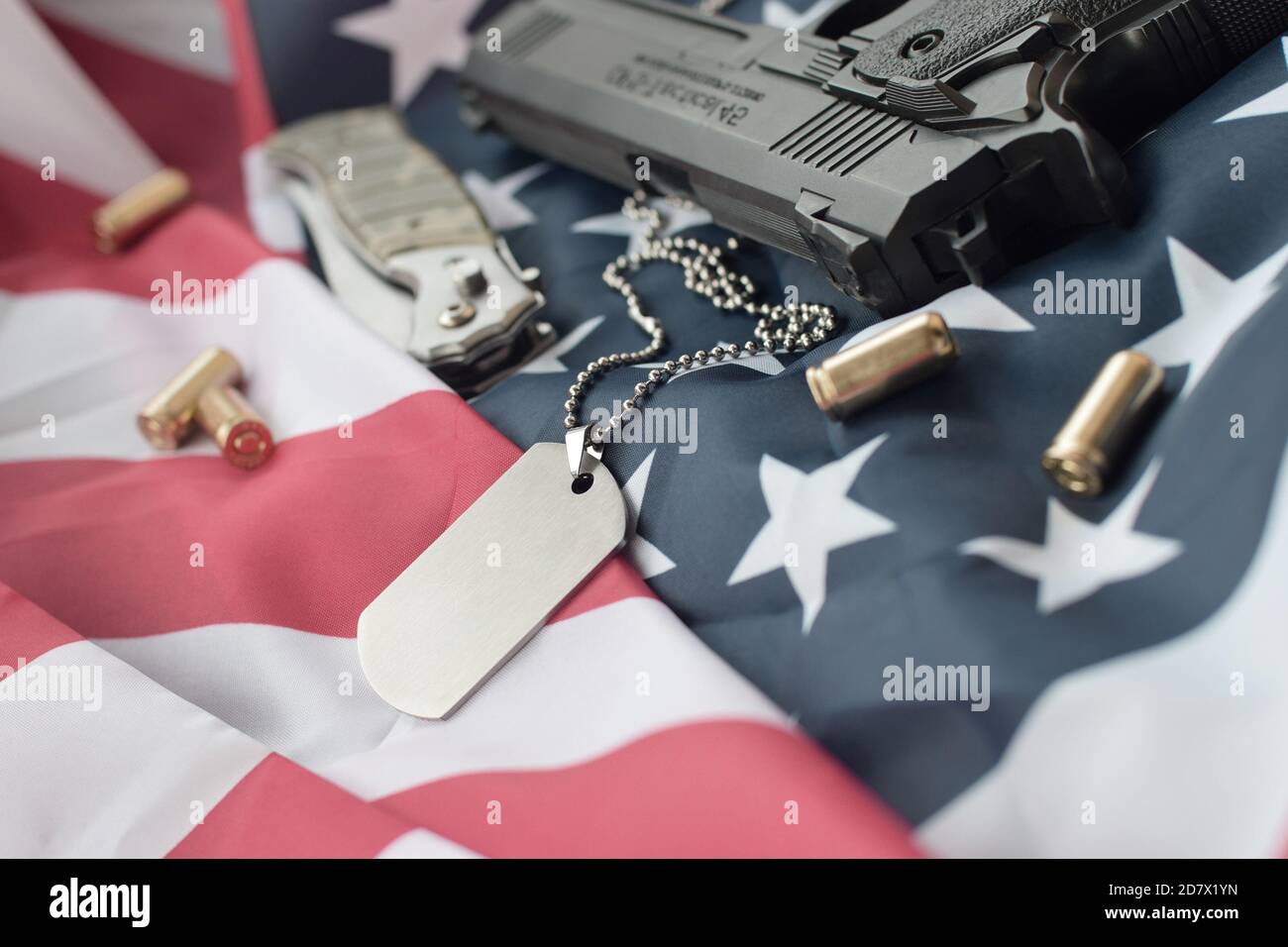 Army Dog tag token with 9mm bullets and pistol lie on folded United ...