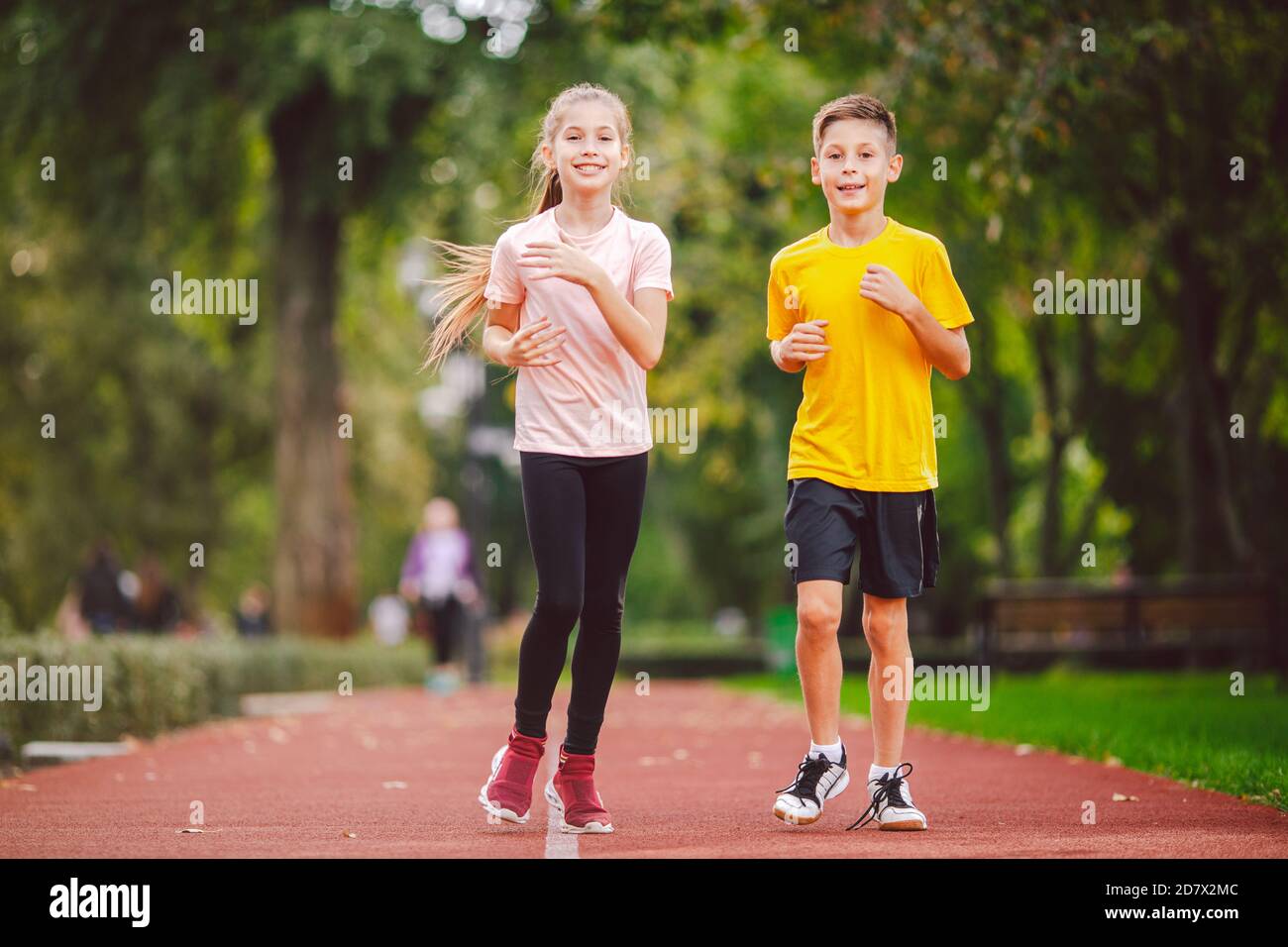 Child fitness, twins kids running on stadium track in city park