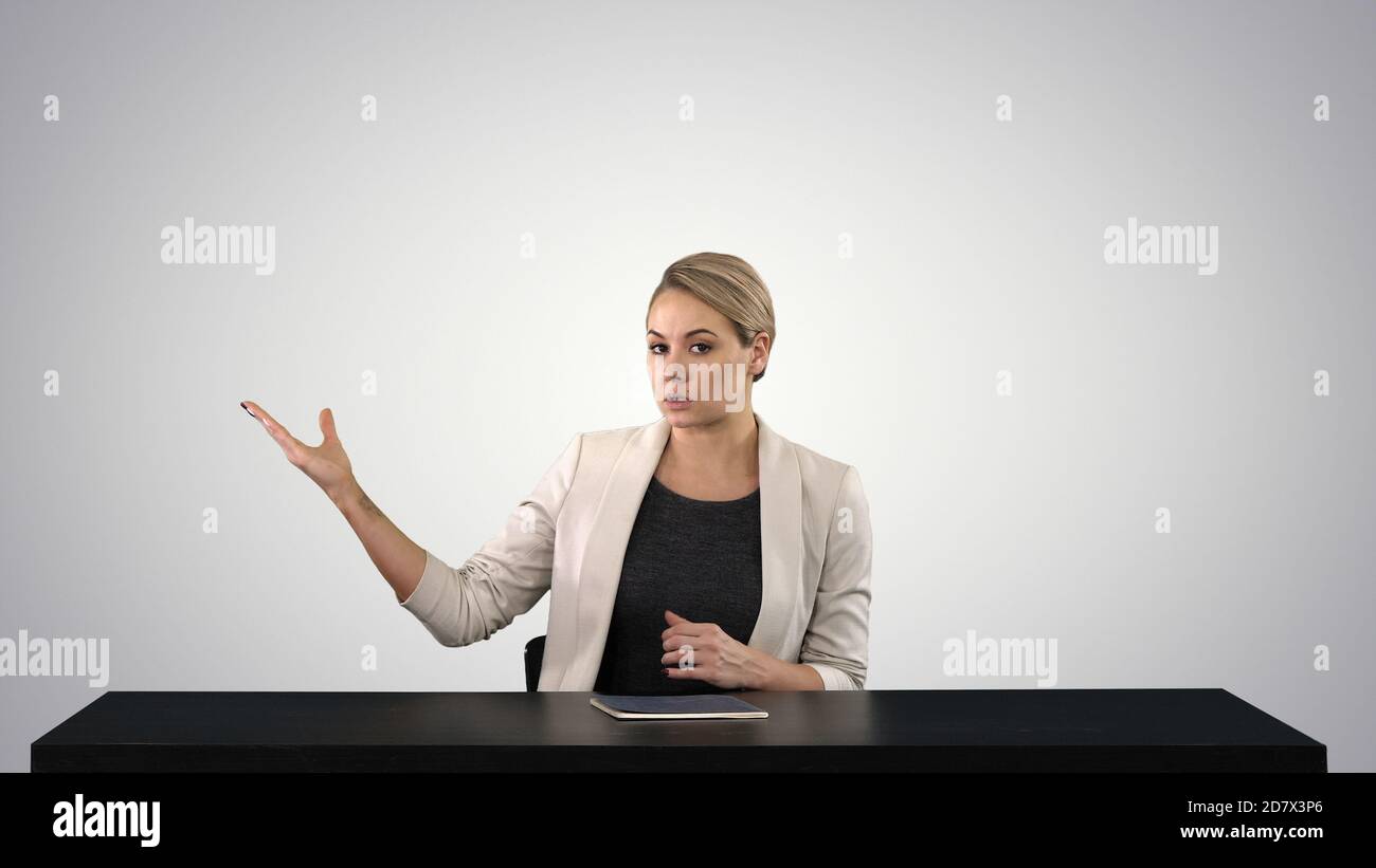 Television anchorwoman at studio pointing to sides on gradient b Stock Photo