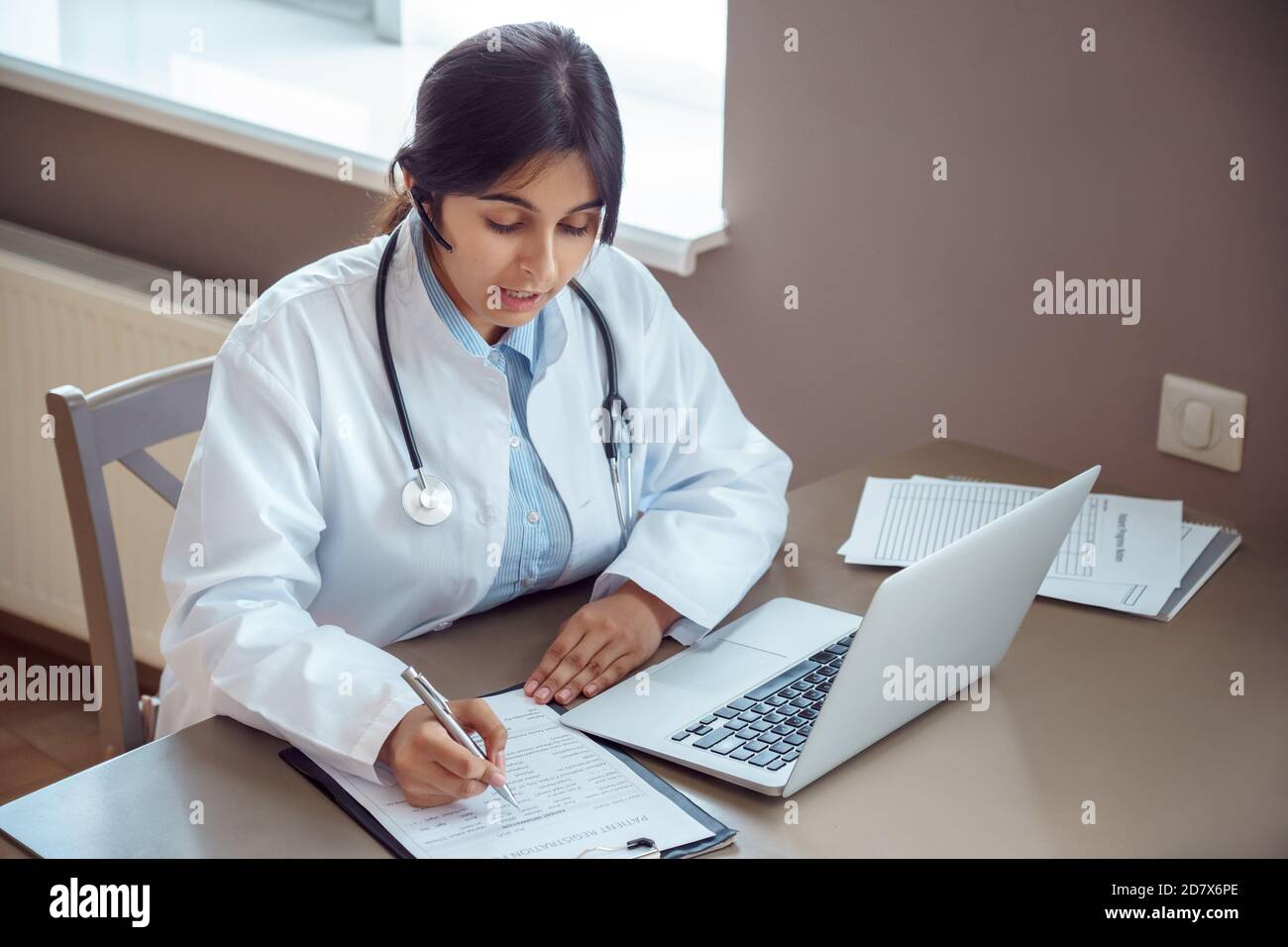 Indian telemedicine doctor wear headset talking to patient by online video call. Stock Photo