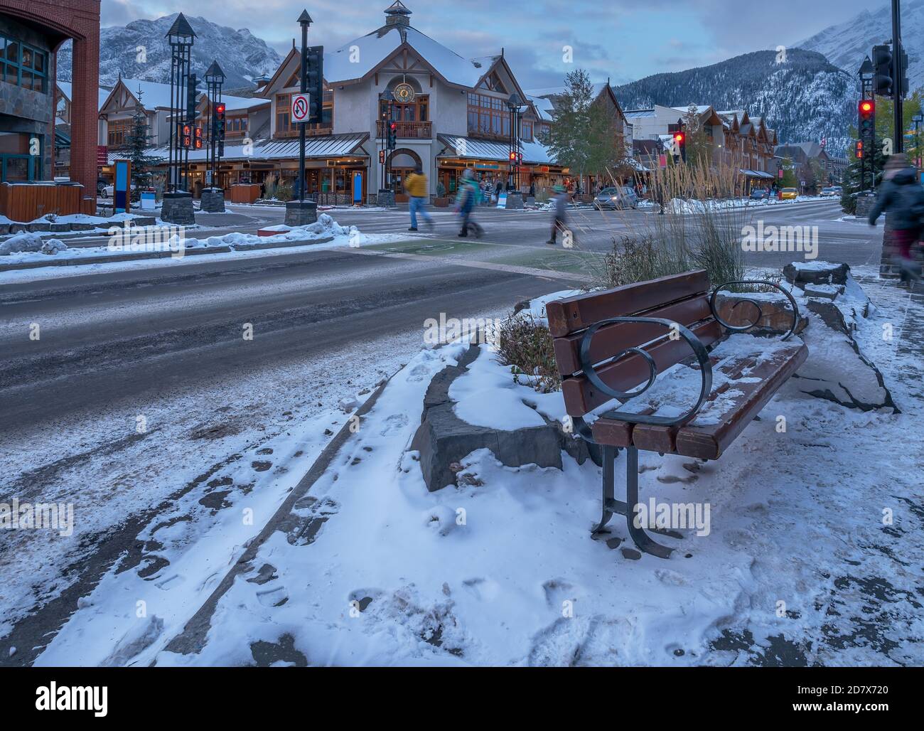Evening view of a street bench, pedestrians and stores on Banff Avenue in Banff, Alberta, Canada Stock Photo