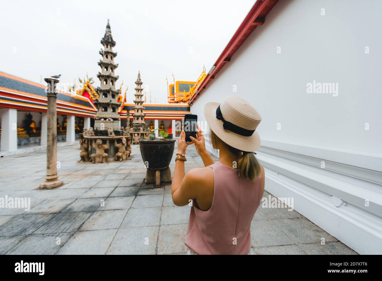 Young woman taking photos with her mobile travel to Thailand with hat walking in Wat Pho at Bangkok Thailand Stock Photo