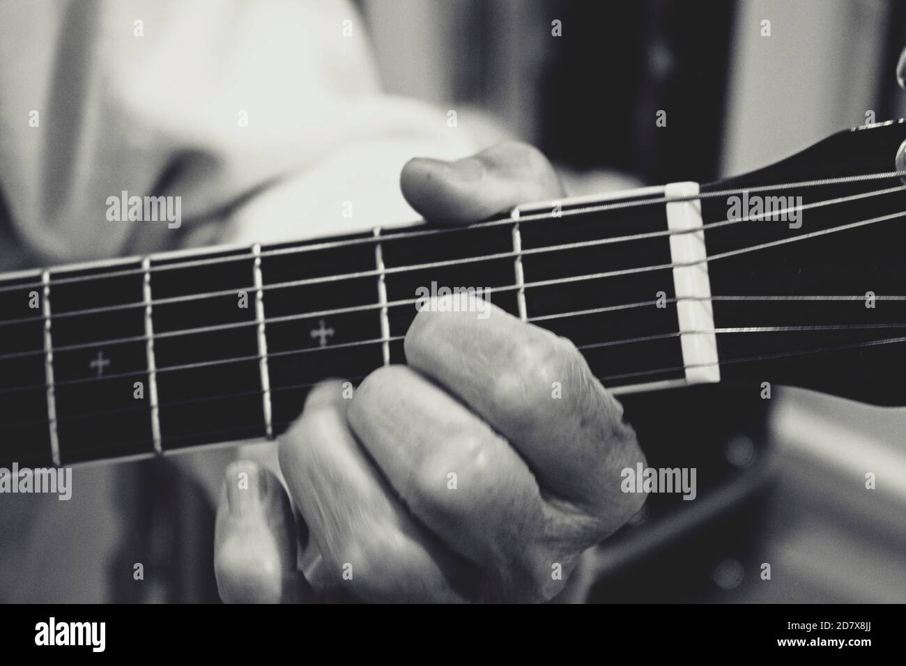 Close up on guitar player with hands on the fretboard, fingerboard, in chord position. Stock Photo