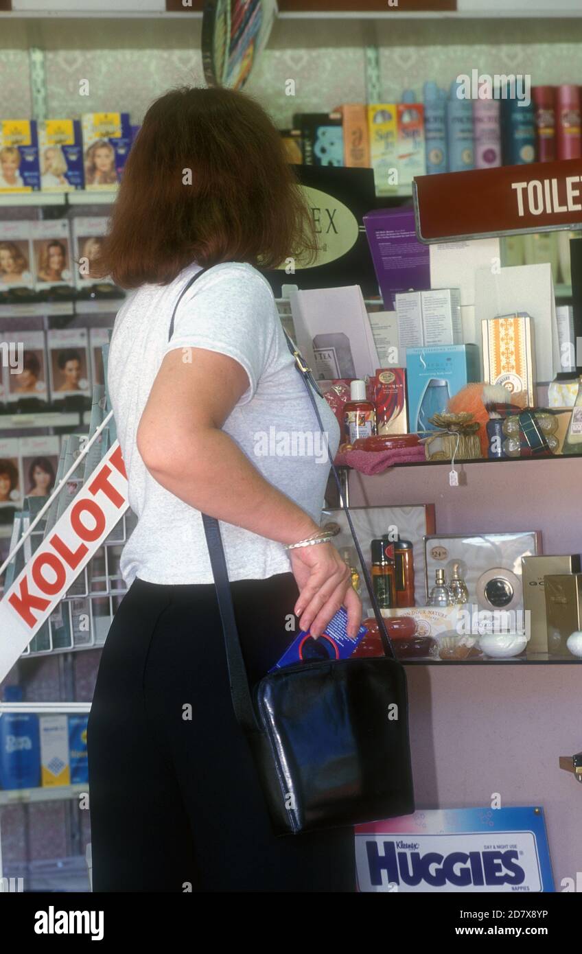 WOMAN IN CHEMIST SHOP ABOUT TO  STEAL A PRODUCT FROM THE SHELF, NEW SOUTH WALES, AUSTRALIA. Stock Photo