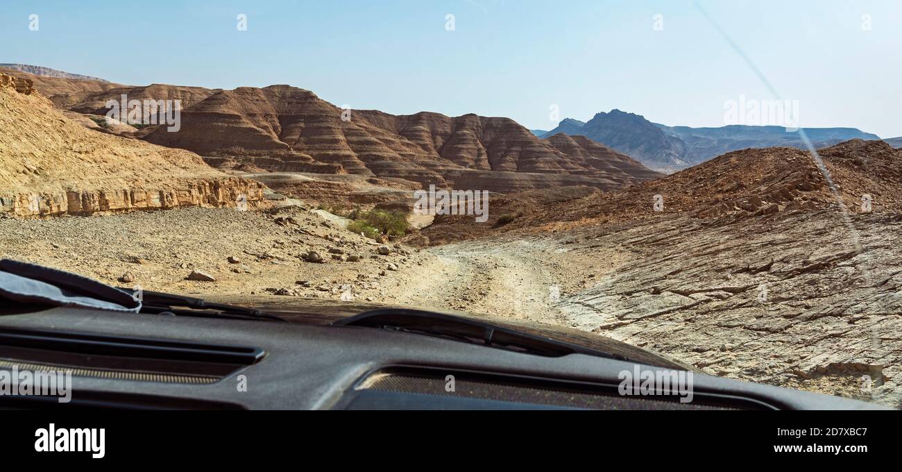 the rugged dekalim palm ascent on the incense route in the makhtesh ramon crater in israel from behind the streaked window of a 4x4 Stock Photo