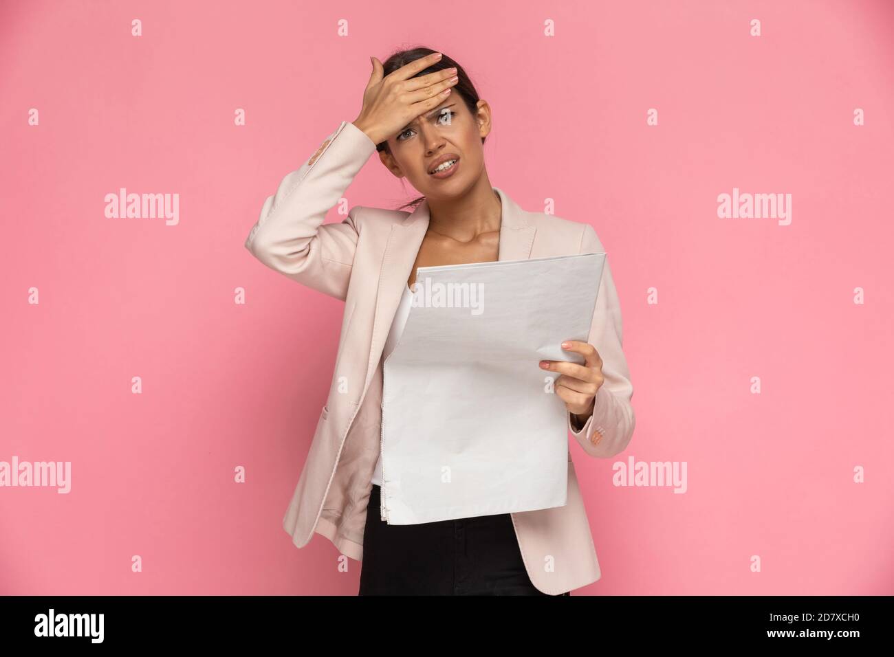 businesswoman beauty slapping her head after reading the newspaper on pink background Stock Photo