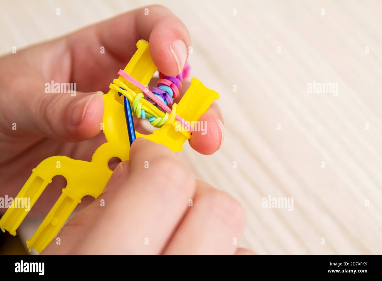 Rubber Band Weaving. Knitting rubber bands with loom knit. Hands of girl weaving wristband of