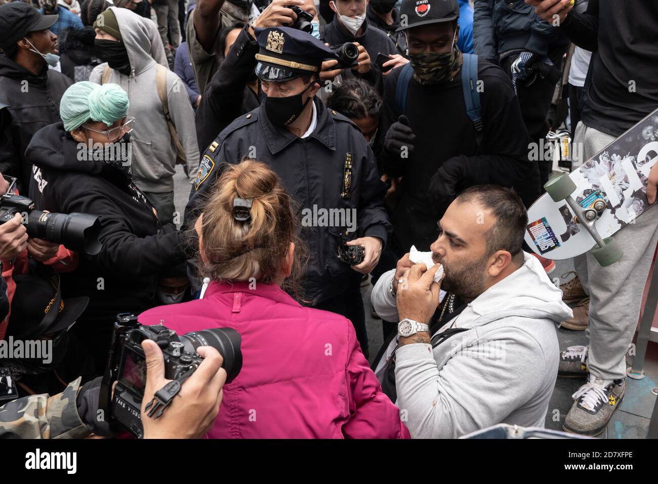NEW YORK, NY – OCTOBER 25, 2020: A bloodied Pro-Trump Supporter seats in Times Square as NYPD Police Officers calls for a medical assistance. Stock Photo