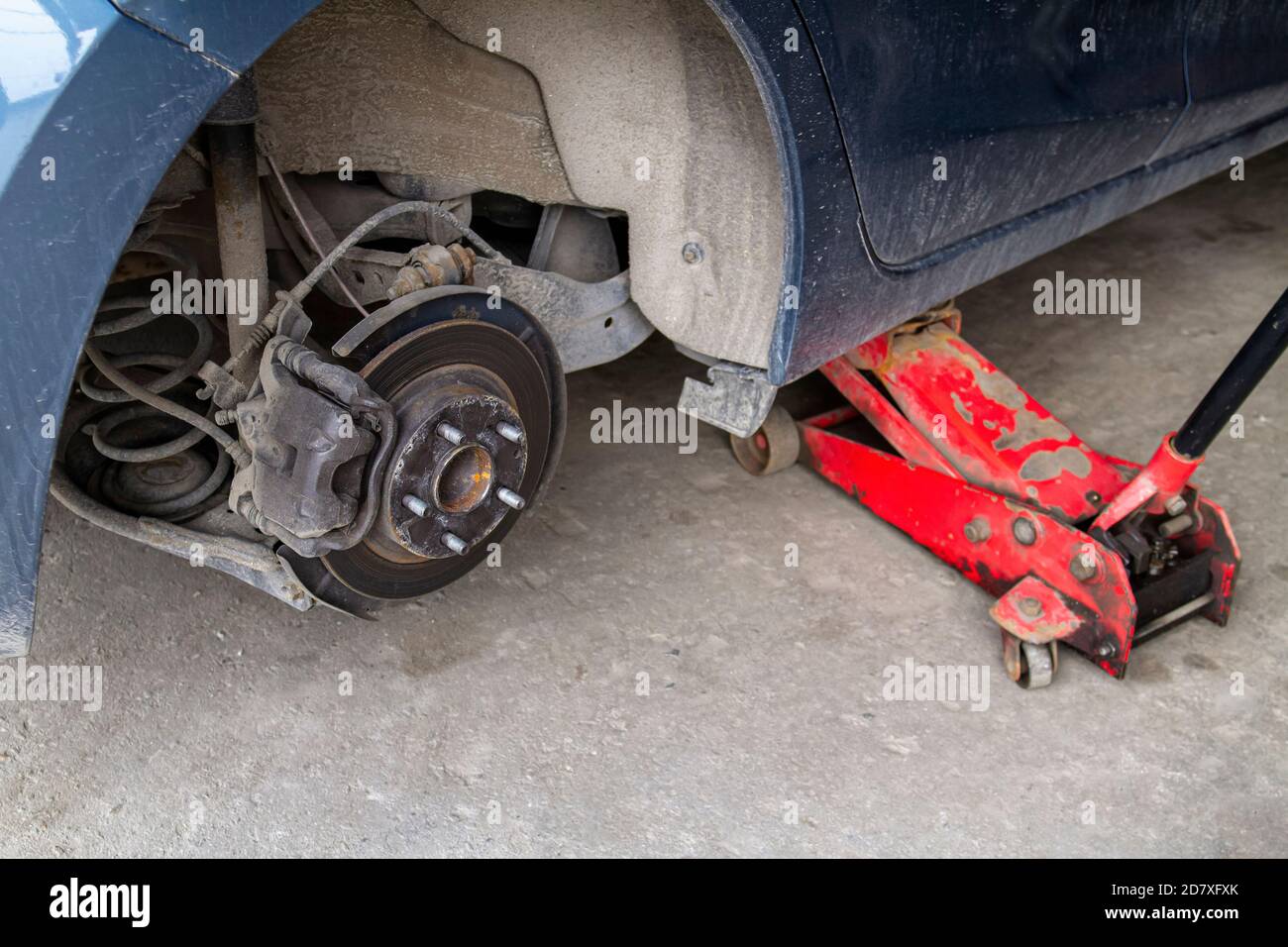 Replacing wheels on a car, jack holds the body in raised position. Car without wheel and lift up by hydraulic, waiting for tire replacement. Stock Photo