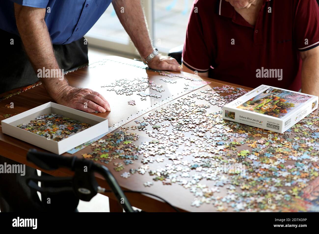 Men in an old peoples home doing a puzzle, Sussex, UK. Stock Photo