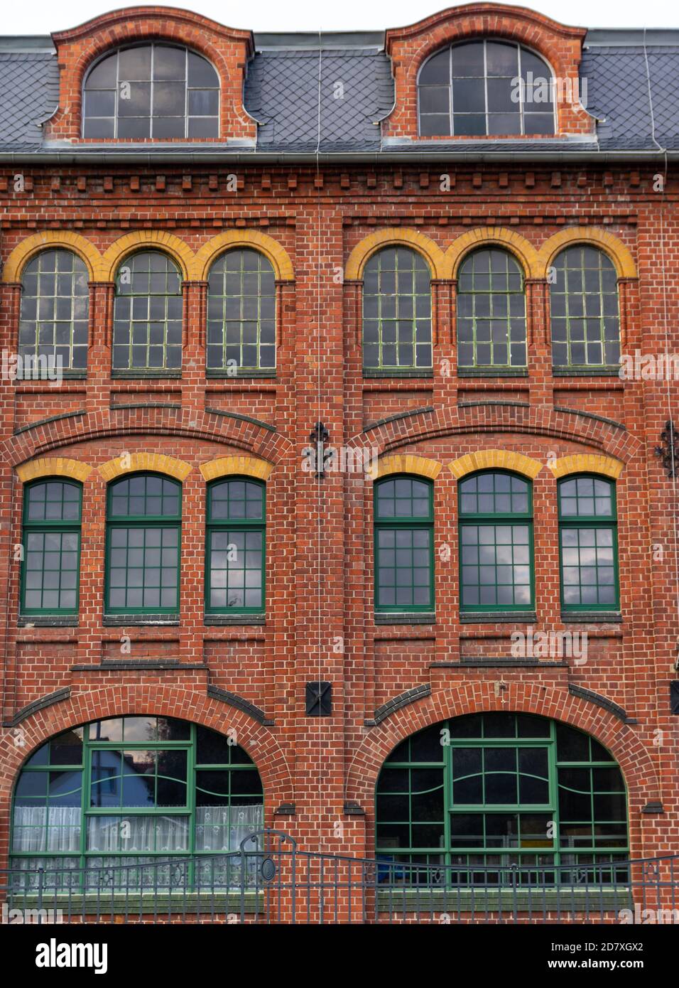 red brick facade of old industrial building with large glass windows Stock Photo